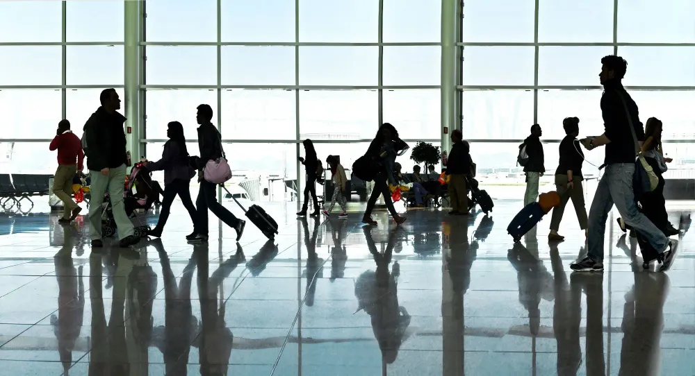 Silhouettes of people walking past a large window in an airport terminal